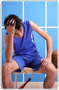 dazed boy basketball player sitting on bench in locker room