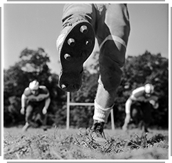 older black-white photo of football player after kicking the ball