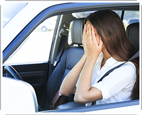 young woman anxious in car with hands over face