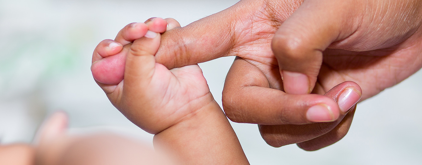 A baby holding an adult's finger