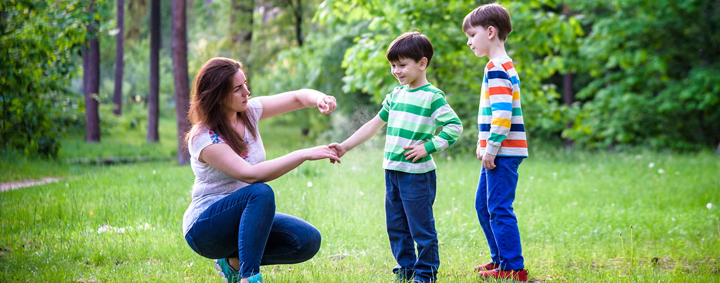 Mom spraying sons with insect repellant