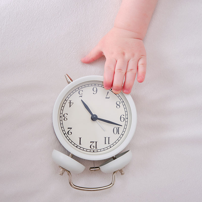 A baby touching an alarm clock